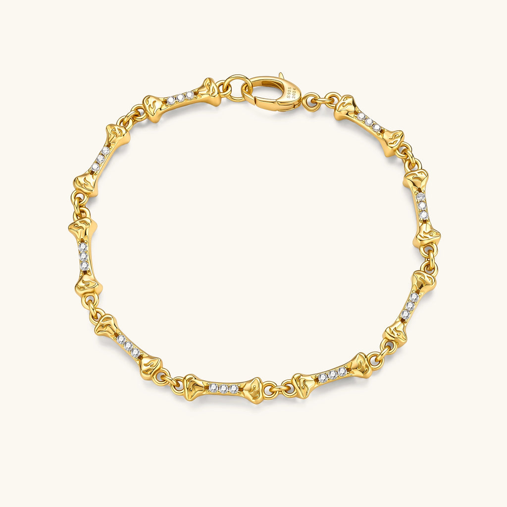 Gold-plated sterling silver bracelet with bone-shaped links, embedded CZ stones, and lobster clasp on light background.