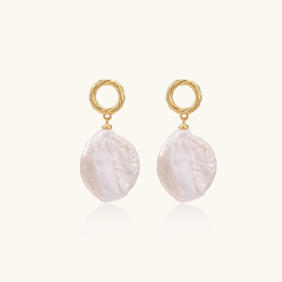 Gold-plated twisted stud earrings with large blush baroque pearls hanging elegantly on white background.