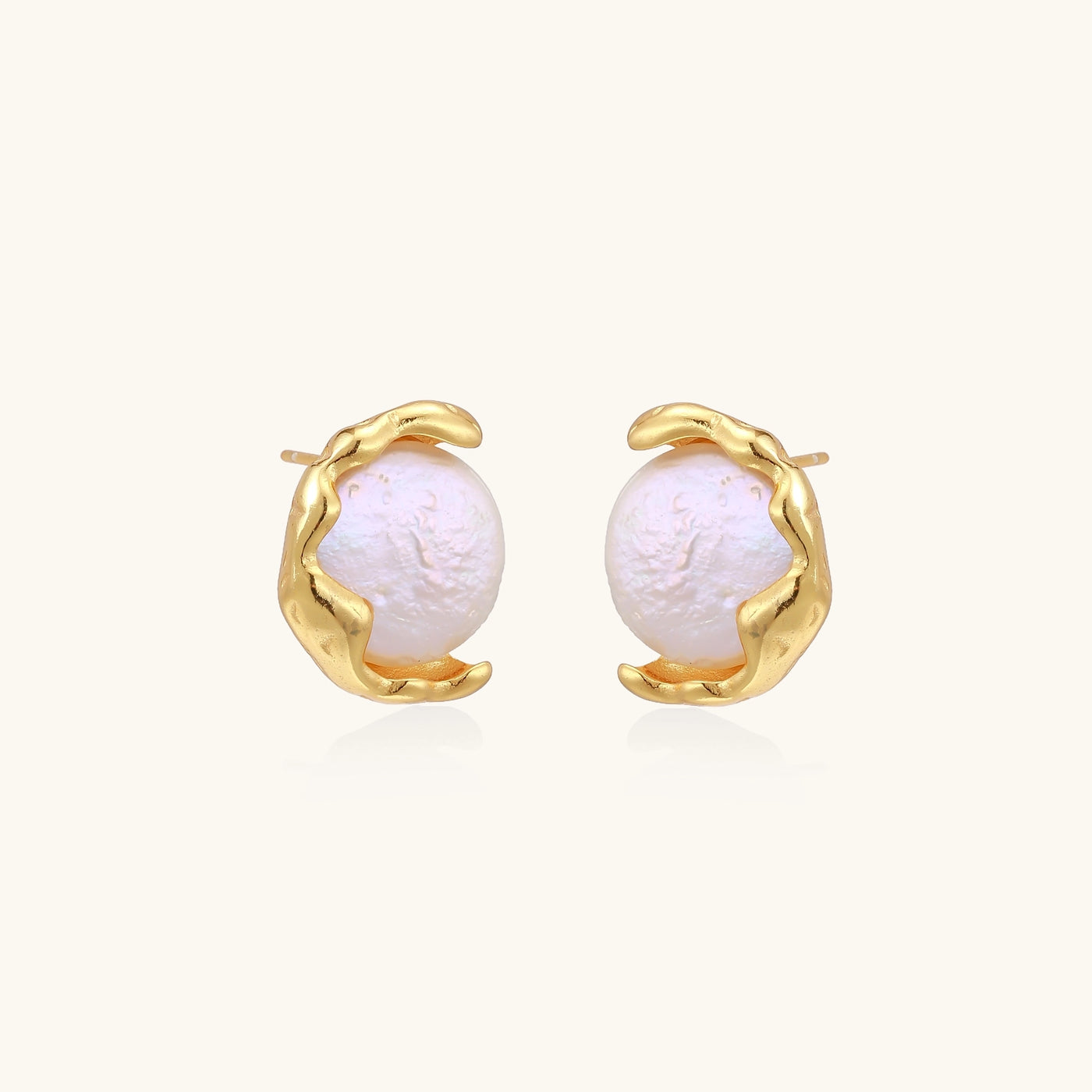 Gold-plated sterling silver stud earrings with organic claw settings cradling lustrous freshwater pearls on white background.