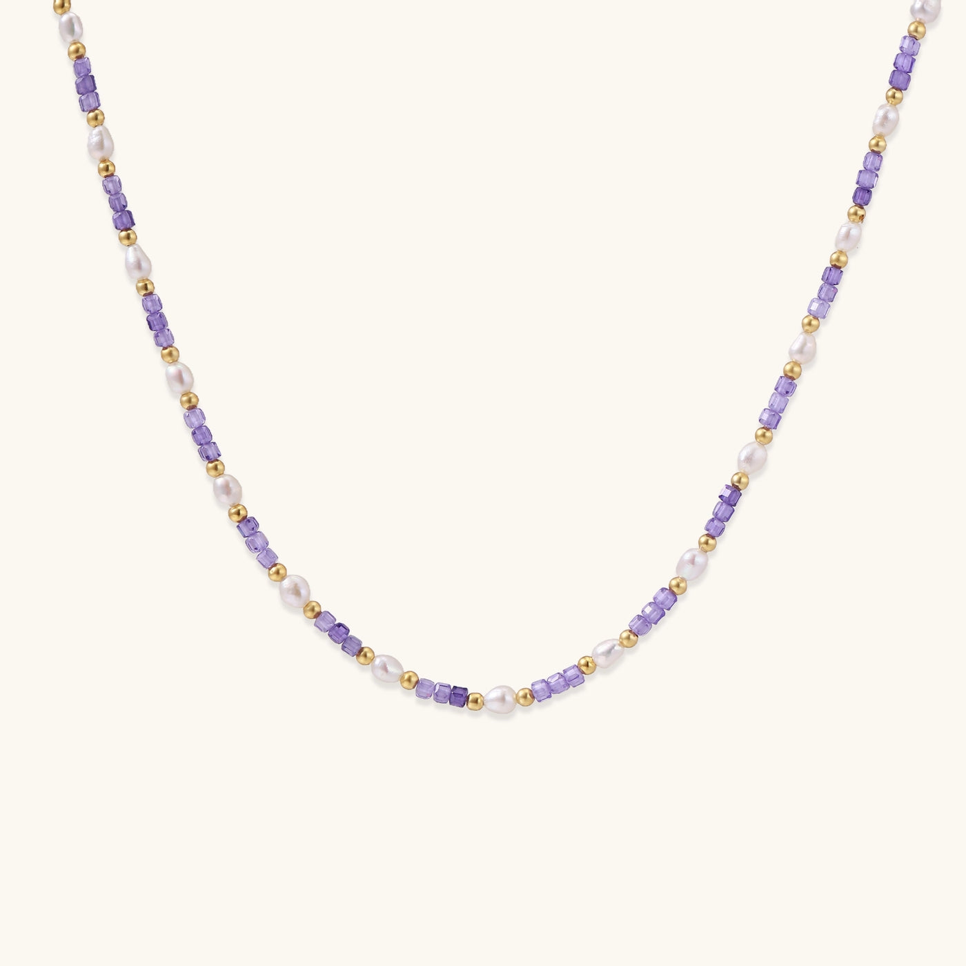 Delicate beaded necklace with alternating purple zirconia stones, white freshwater pearls, and gold-plated spacers on cream background.