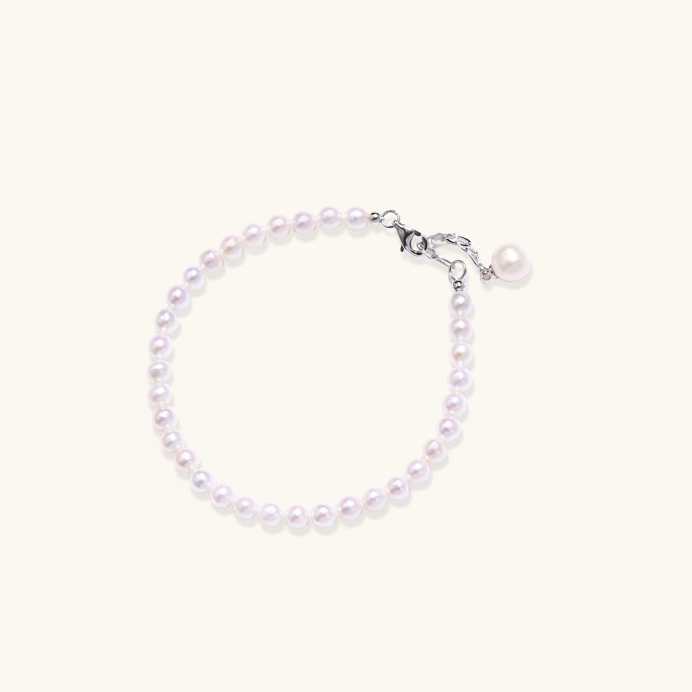 Delicate sterling silver bracelet with small freshwater pearls and adjustable chain on neutral background.