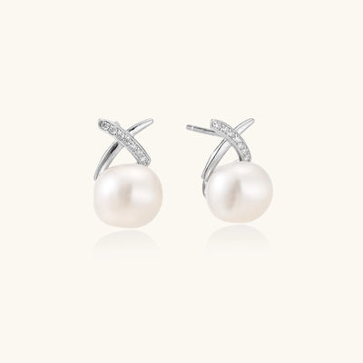 Sterling silver cross-shaped stud earrings with round freshwater pearls dangling below on white background.