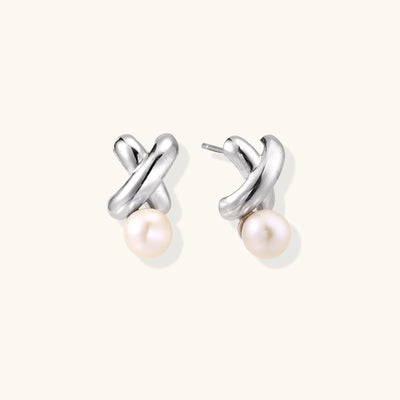 Sterling silver twisted stud earrings with round freshwater pearls on cream background, showing polished finish