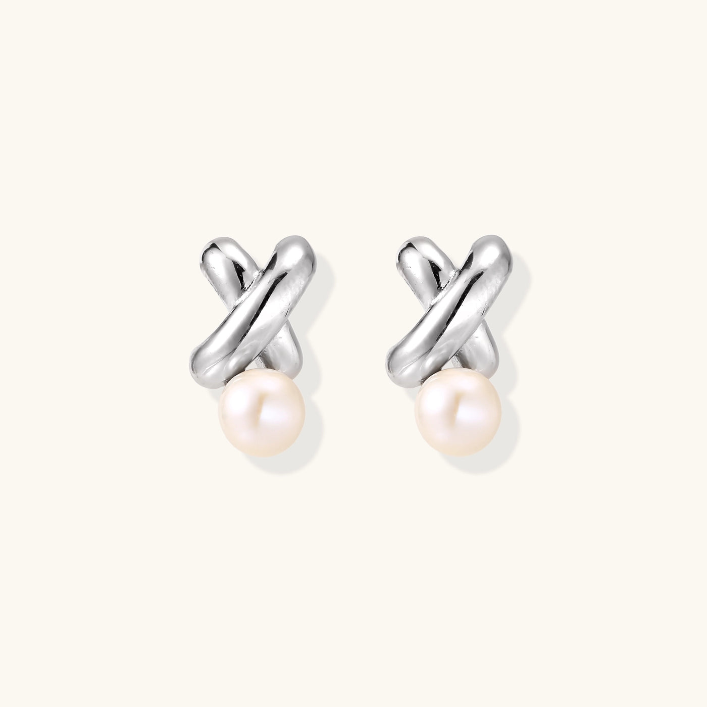 Sterling silver twisted stud earrings with round freshwater pearls on cream background, showing polished finish
