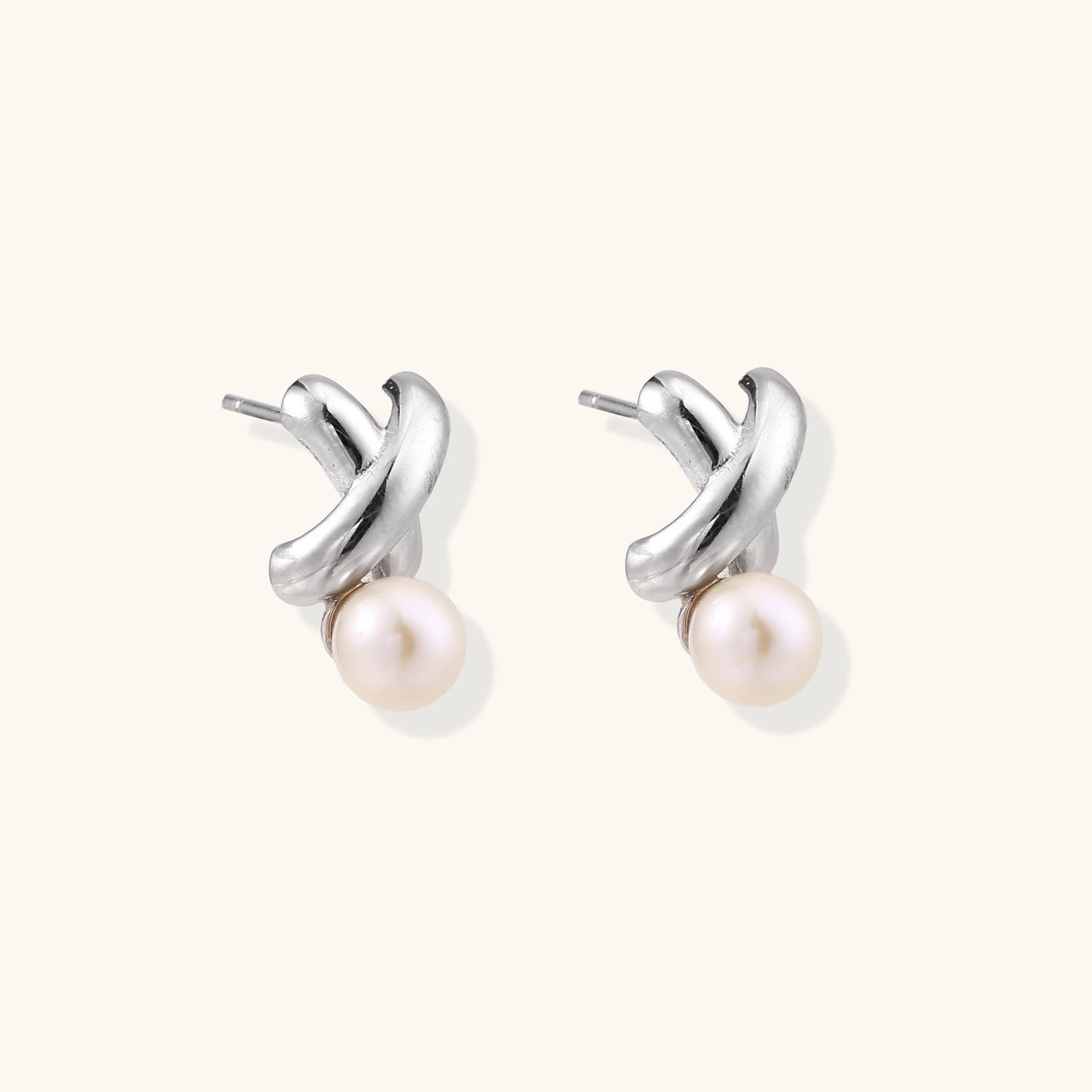 Sterling silver twisted stud earrings with round freshwater pearls on cream background, showing polished finish