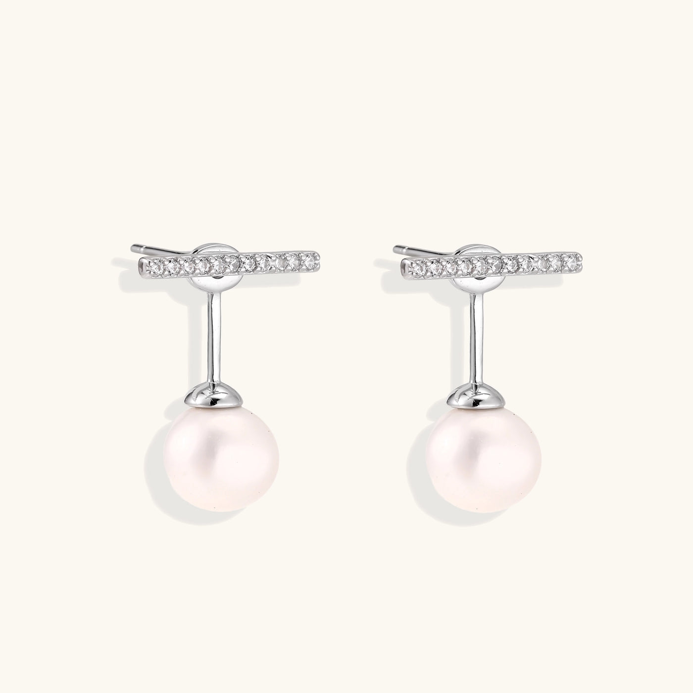 Sterling silver bar stud earrings with freshwater pearl drops on white background, minimalist jewelry design