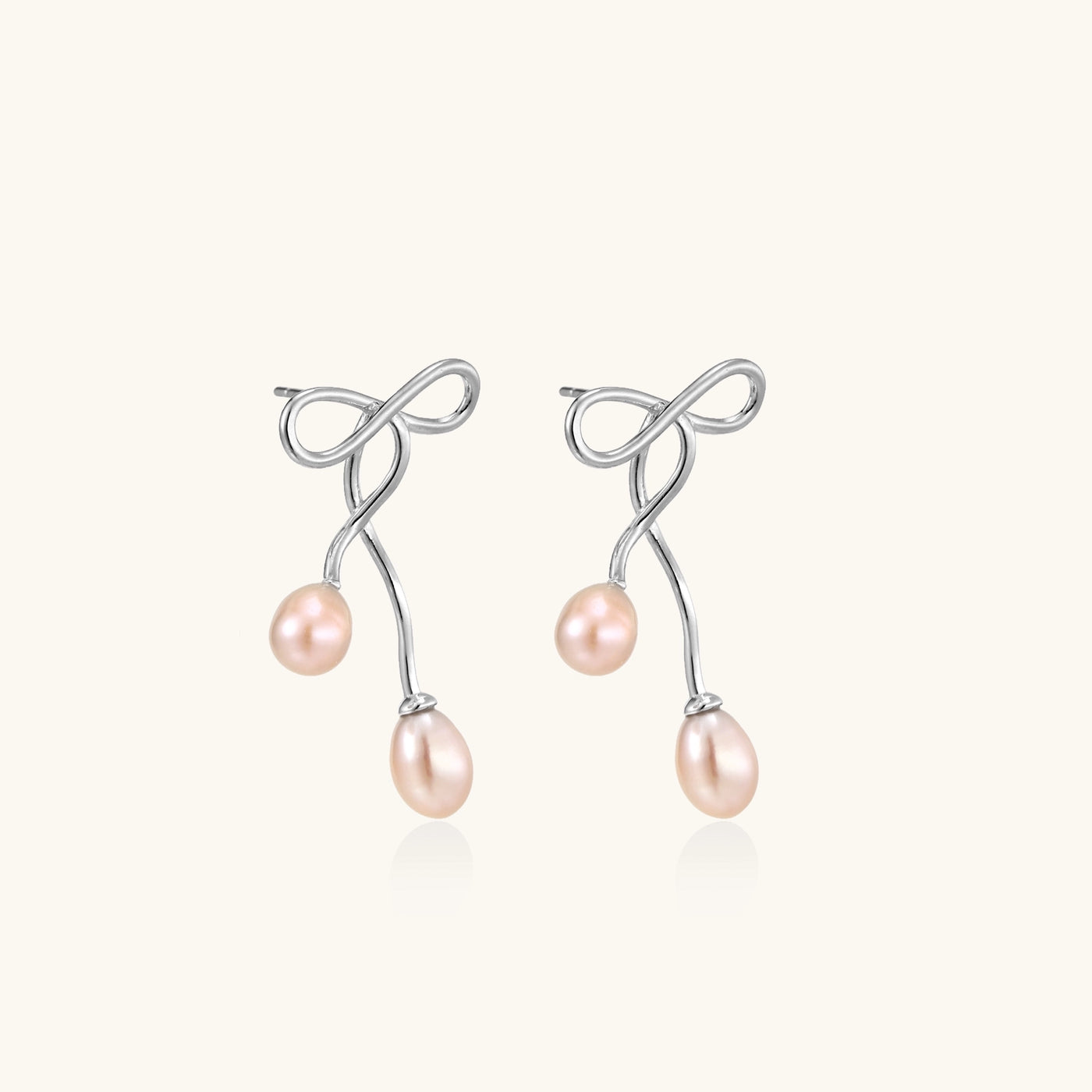 Delicate sterling silver wire earrings with organic bow shapes and two pink freshwater pearls on white background