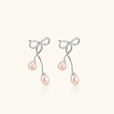 Delicate sterling silver wire earrings with organic bow shapes and two pink freshwater pearls on white background