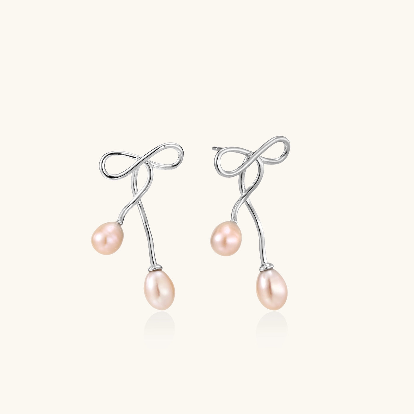 Delicate sterling silver wire earrings with organic bow shapes and two pink freshwater pearls on white background