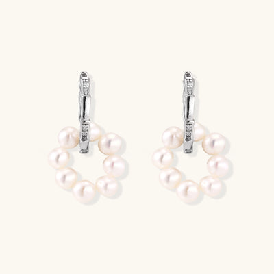 Sterling silver huggie hoop earrings with clustered white freshwater pearls and crystal accents on white background.