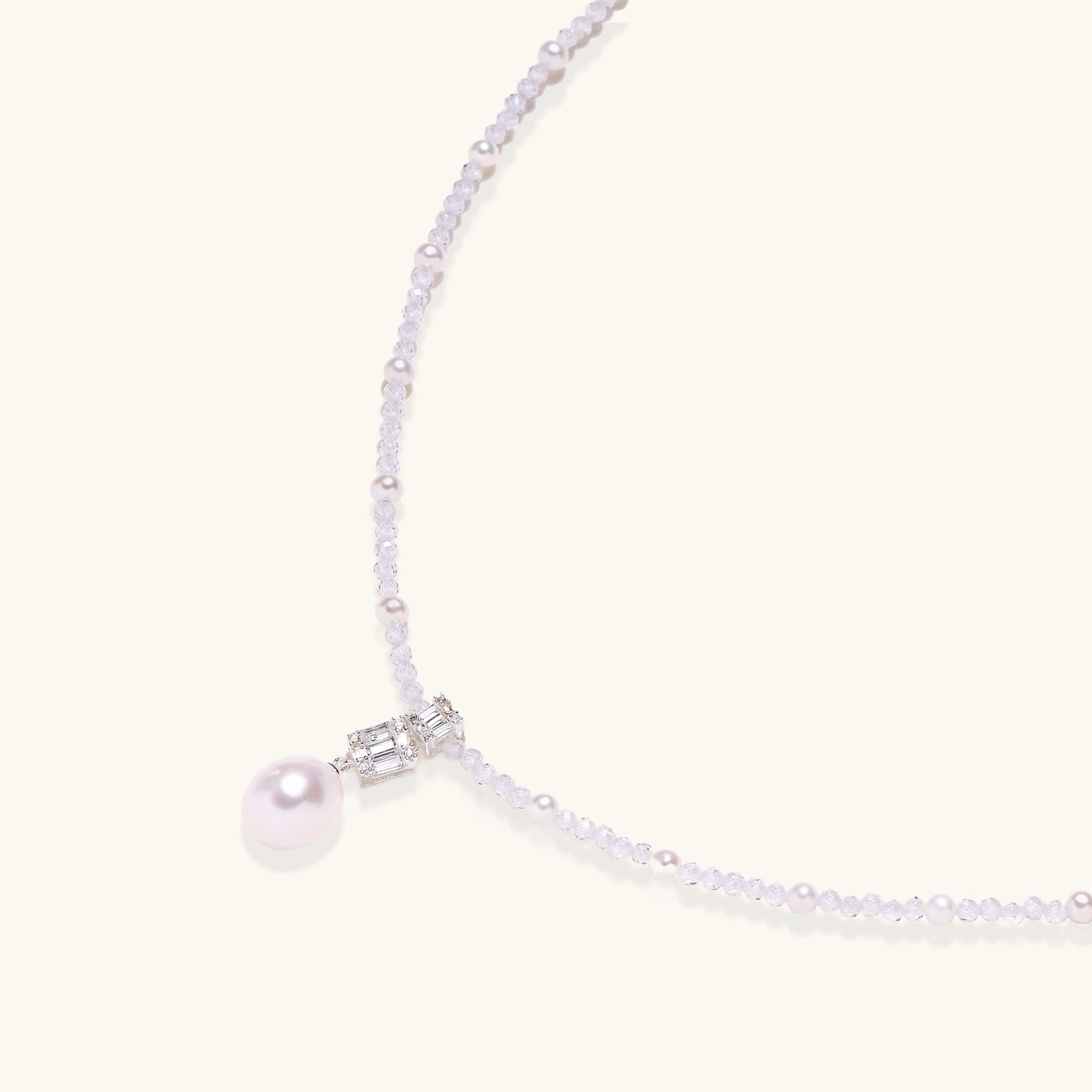 Delicate beaded necklace with lavender crystals, white pearls, and crystal pendant with pearl drop on white background.