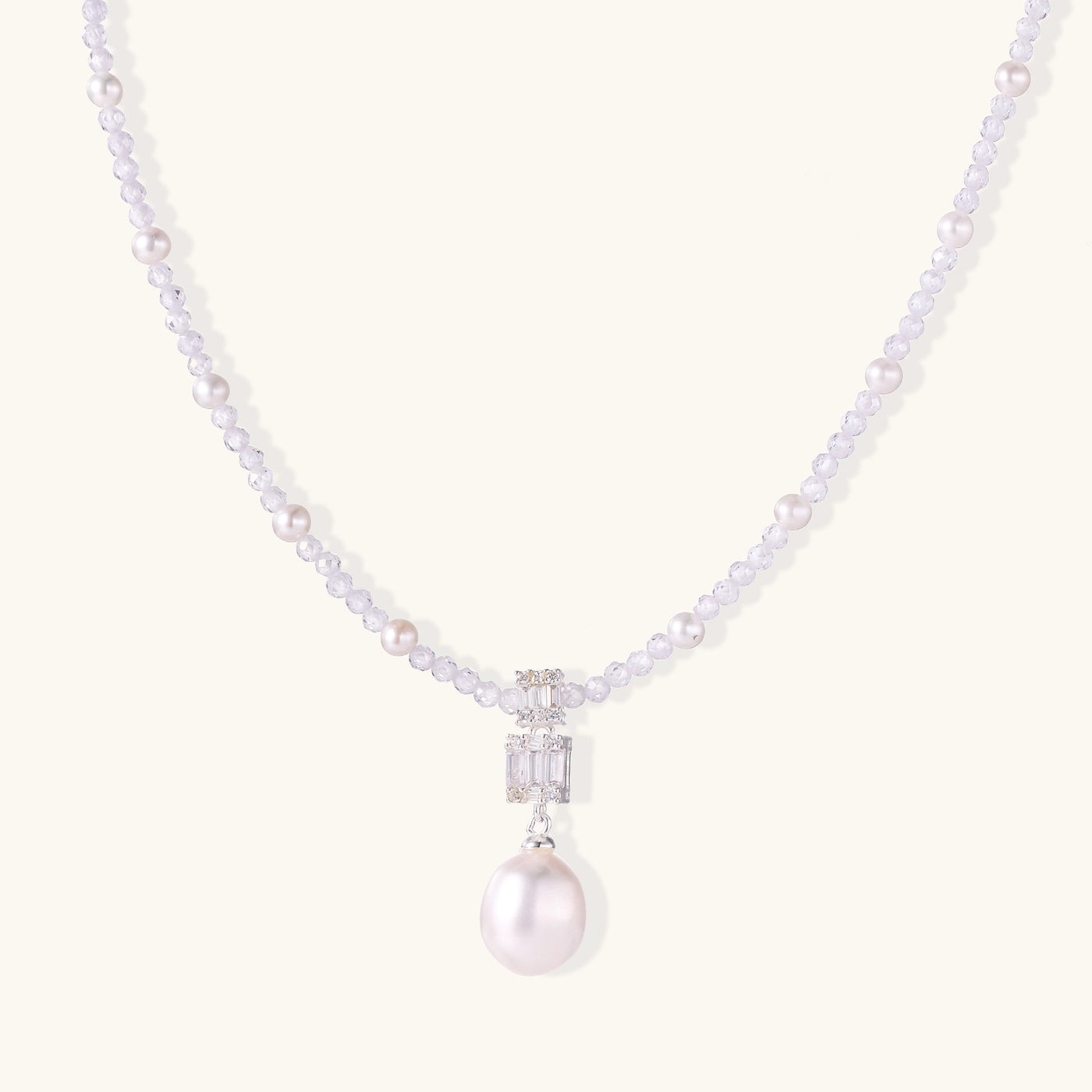 Delicate beaded necklace with lavender crystals, white pearls, and crystal pendant with pearl drop on white background.