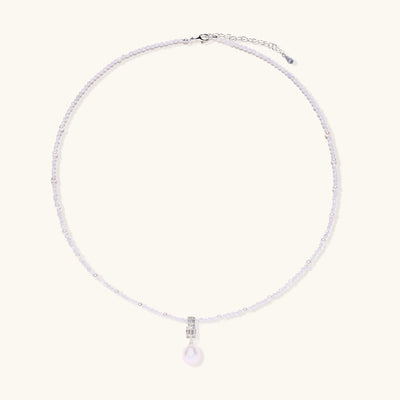Delicate beaded necklace with lavender crystals, white pearls, and crystal pendant with pearl drop on white background.