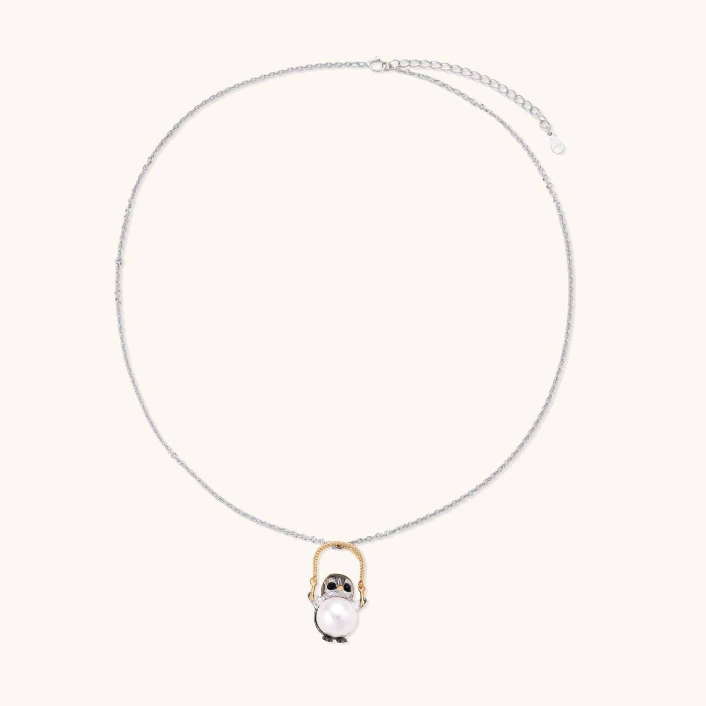 Silver owl pendant holding a round freshwater pearl on an adjustable chain against white background