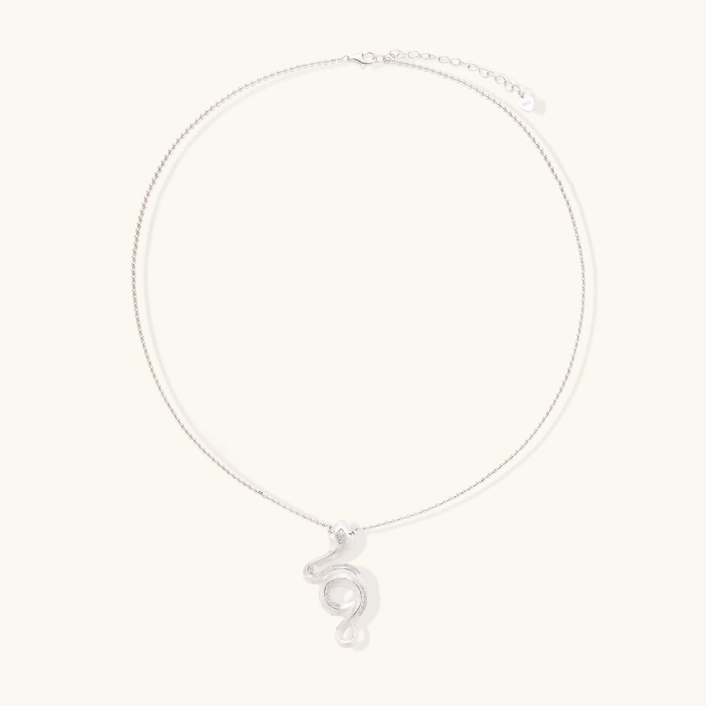 Sterling silver snake pendant necklace with zirconia crystals on adjustable chain against cream background