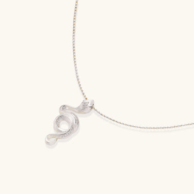 Sterling silver snake pendant necklace with zirconia crystals on adjustable chain against cream background