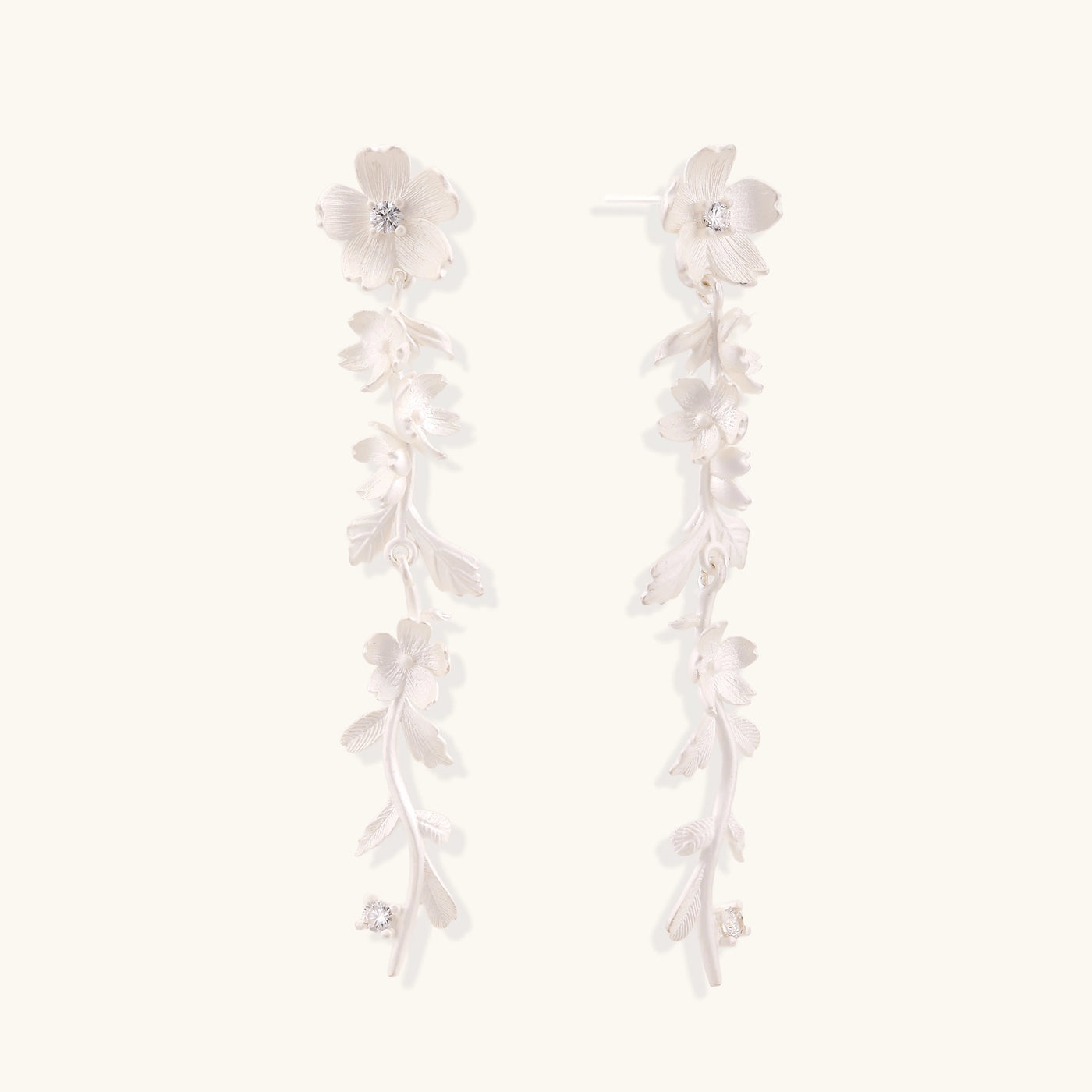 Pair of sterling silver dangle earrings with intricate leaf vine patterns and crystal accents on white background.