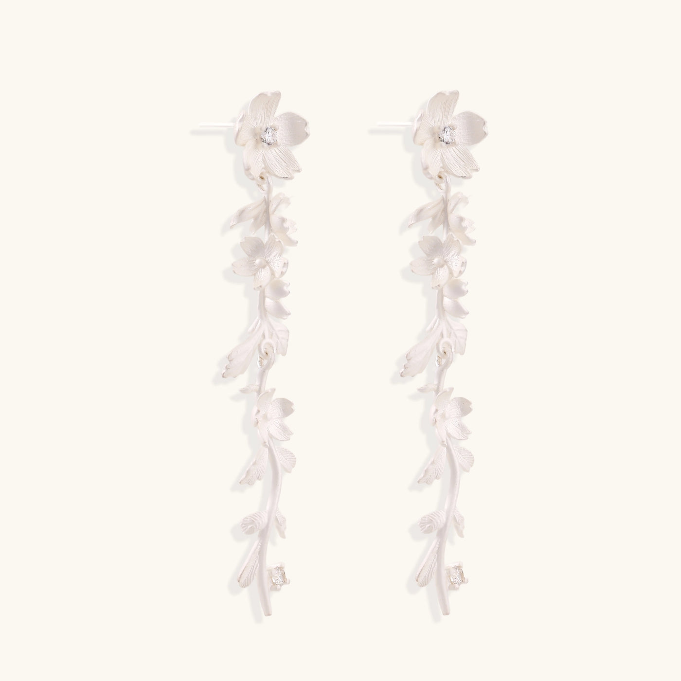 Pair of sterling silver dangle earrings with intricate leaf vine patterns and crystal accents on white background.