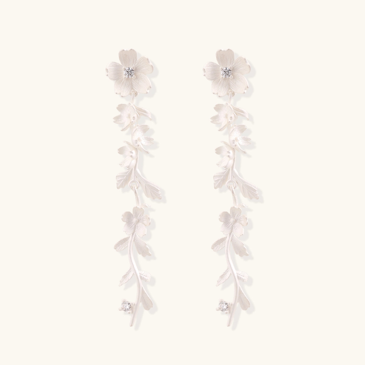 Pair of sterling silver dangle earrings with intricate leaf vine patterns and crystal accents on white background.