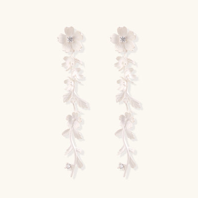 Pair of sterling silver dangle earrings with intricate leaf vine patterns and crystal accents on white background.
