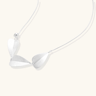 Delicate sterling silver necklace with brushed leaf pendants distributed along a fine chain on white background.