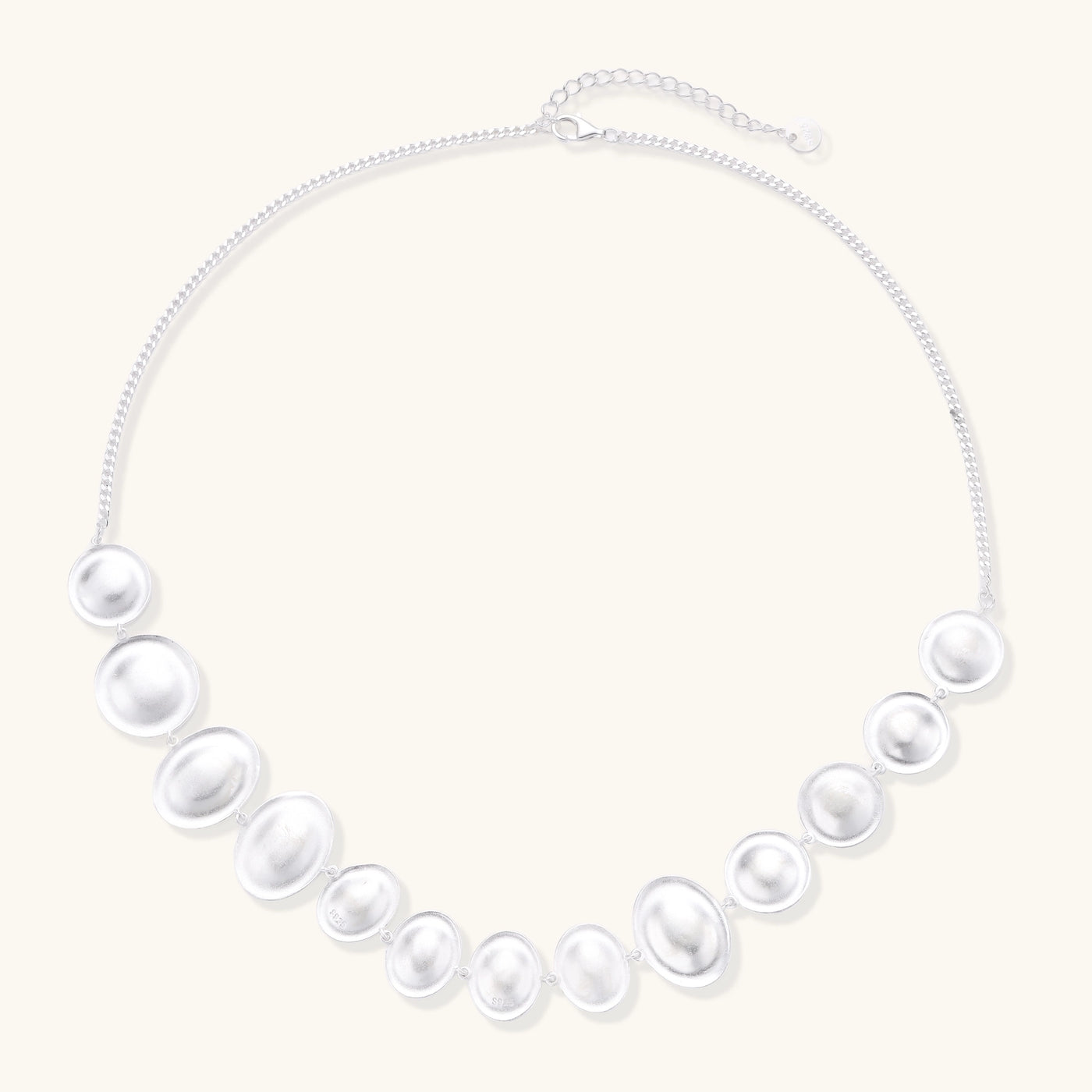 Sterling silver necklace with asymmetrically placed white pearls of varying sizes on neutral background