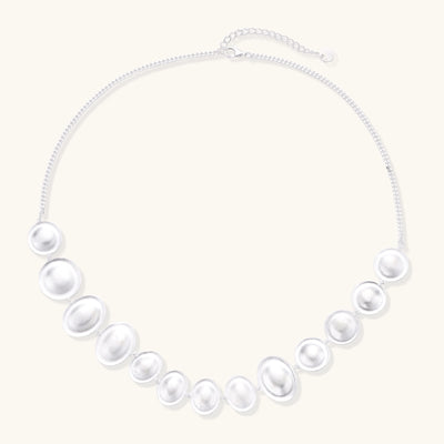 Sterling silver necklace with asymmetrically placed white pearls of varying sizes on neutral background