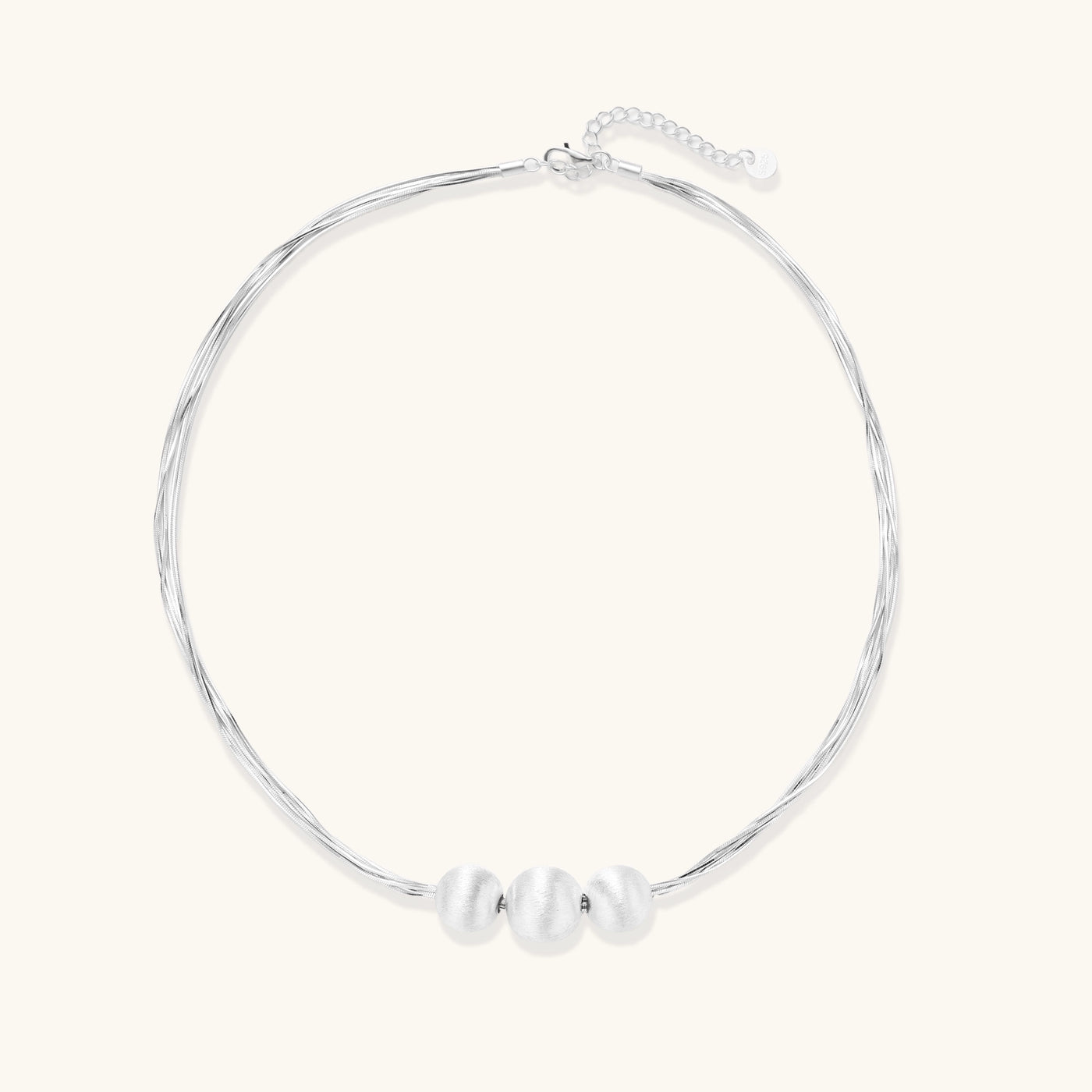 Multi-strand sterling silver necklace with three polished round beads clustered at center on white background.