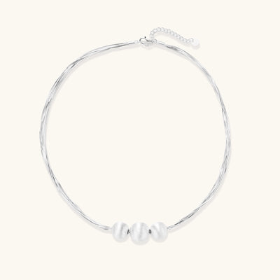 Multi-strand sterling silver necklace with three polished round beads clustered at center on white background.