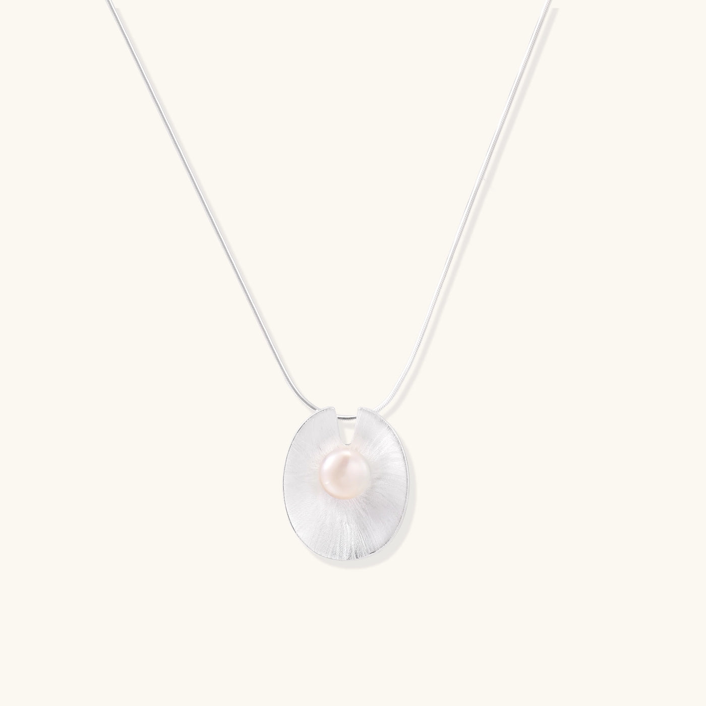 Delicate sterling silver necklace with oval iridescent pendant and central freshwater pearl on white background