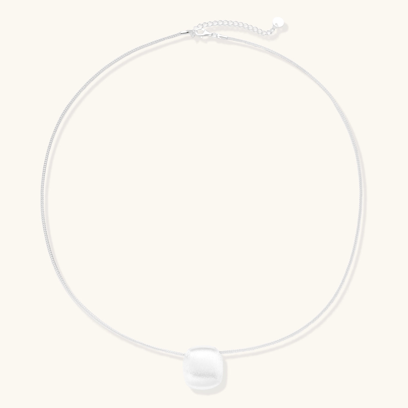 Minimalist sterling silver necklace with brushed square pendant on adjustable chain against white background.