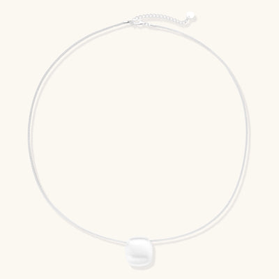 Minimalist sterling silver necklace with brushed square pendant on adjustable chain against white background.