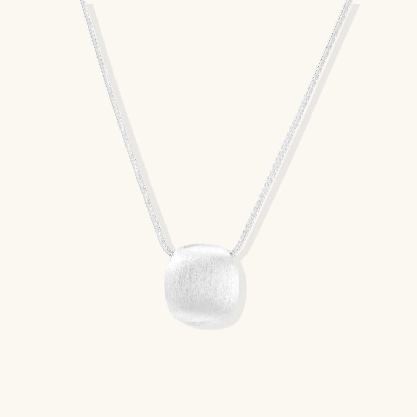 Minimalist sterling silver necklace with brushed square pendant on adjustable chain against white background.
