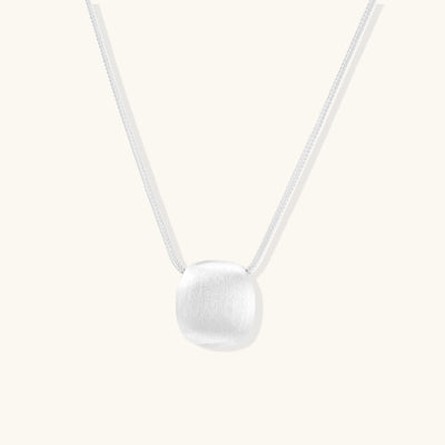 Minimalist sterling silver necklace with brushed square pendant on adjustable chain against white background.