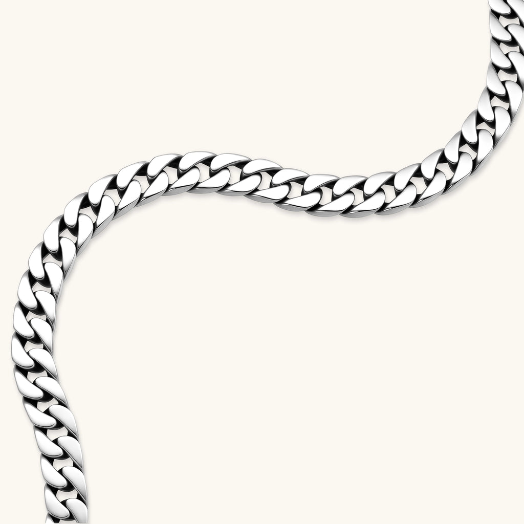 Polished 925 sterling silver Cuban link chain necklace, 550mm length, shown flat and draped on cream background.