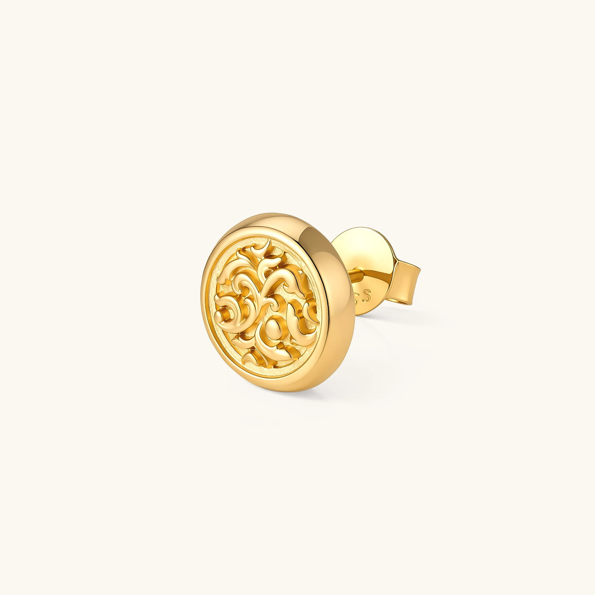 Side view of a round gold stud earring with raised baroque scroll engraving, domed border, and butterfly push-back closure.