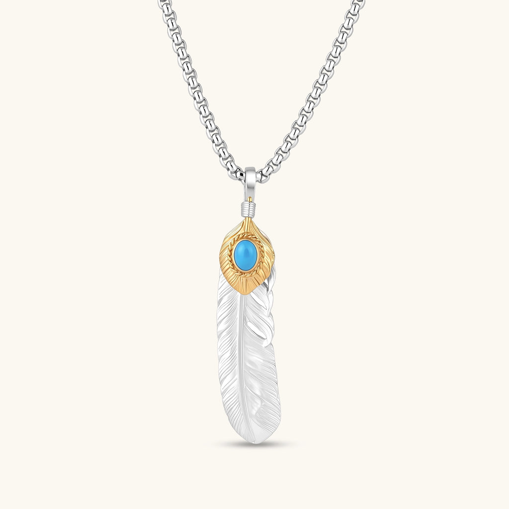 Sterling silver feather pendant with a gold-tone leaf accent and oval blue stone, shown on a box chain against a cream background.