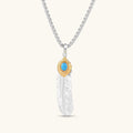Sterling silver feather pendant with a gold-tone leaf accent and oval blue stone, shown on a box chain against a cream background.